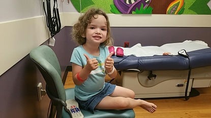 Little girl giving thumbs up in a doctors office